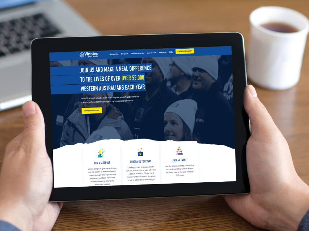 Hands holding an ipad with the Fundraising hub website homepage showing